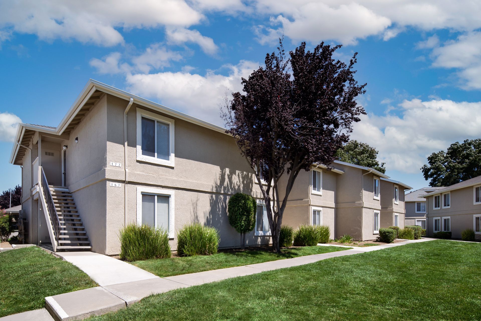 A two-storey River Run apartment building with an exterior stair, lawn and walkway