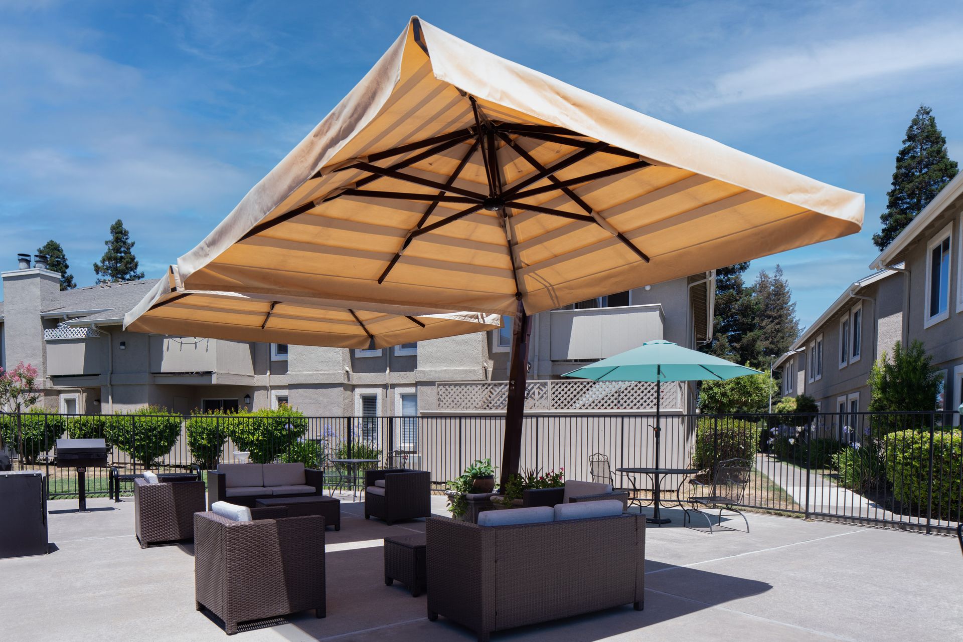 Shaded outdoor lounge seating beneath a large canopy umbrella beside the BBQ area